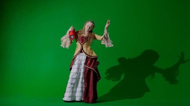 Tarihsel kişi modern yaşam tarzı reklamı. Krom anahtar yeşil ekranda eski bir kıyafet giymiş kadın. Rönesans tarzı elbise giymiş, elinde müzik hoparlörü olan bir kadın şarkı söyleyip dans ediyor..
