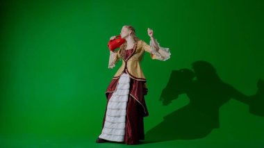 Tarihsel kişi modern yaşam tarzı reklamı. Krom anahtar yeşil ekranda eski bir kıyafet giymiş kadın. Rönesans tarzı elbise giymiş, elinde müzik hoparlörü olan bir kadın şarkı söyleyip dans ediyor..