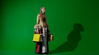 Tarihsel kişi modern yaşam tarzı reklamı. Krom anahtar yeşil ekran arka planında eski giysili bir kadın. Rönesans tarzı elbisesi ve bir sürü hediye çantası olan bir kadın..