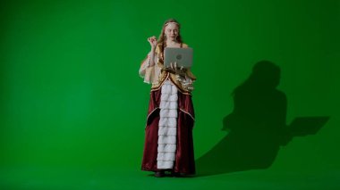 Tarihsel kişi modern yaşam tarzı reklamı. Krom anahtar yeşil ekran arka planda antik kıyafetli bir kadın. Rönesans tarzı elbise giymiş bir kadın dizüstü bilgisayarda mesaj yazıyor..