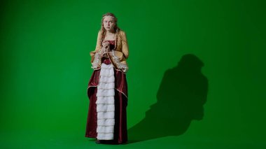 Tarihsel kişi modern yaşam tarzı reklamı. Krom anahtar yeşil ekran arka planda antik kıyafetli bir kadın. Rönesans tarzı elbiseli bir kadın kameraya bakıyor, korkmuş bir surat..