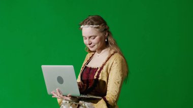 Tarihsel kişi modern yaşam tarzı reklamı. Krom anahtar yeşil ekran arka planda antik kıyafetli bir kadın. Rönesans tarzı elbise giymiş bir kadın dizüstü bilgisayarda mesaj yazıyor..