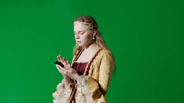 Tarihsel kişi modern yaşam tarzı reklamı. Krom anahtar yeşil ekran arka planında eski giysili bir kadın. Rönesans tarzı elbiseli kadın akıllı telefonuyla mesaj atıyor..