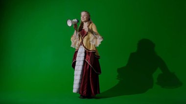 Tarihsel kişi modern yaşam tarzı reklamı. Krom anahtar yeşil ekran arka planında eski giysili bir kadın. Rönesans tarzı elbise giymiş bir kadın elinde megafonla reklam sunuyor..