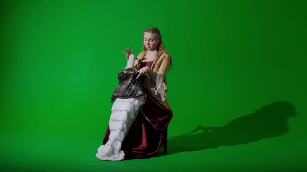 歴史的人物現代ライフスタイル広告 クロマキーの緑色の背景に古代の服を着た女性 ルネッサンスドレスの女性は ゴミ袋を保持して内部を見るとゴミ箱を取り出します — ストック動画