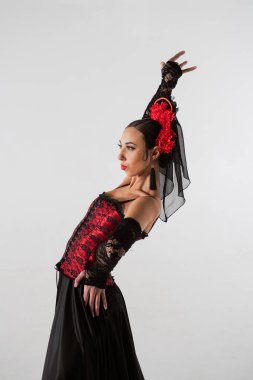 Modern koreografi bir dans. Beyaz arka planda dans eden kadın dansçı. Flamenko tarzı elbise giyen kadın stüdyoda elleri ve vücuduyla zarif İspanyol dansı hareketleri sergiliyor..