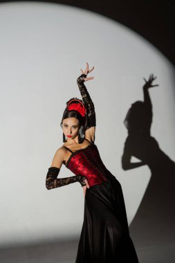 Modern koreografi bir dans. Sahne ışıkları altında siyah arka planda dans eden bir kadın. Kırmızı-siyah elbiseli İspanyol dansçı tutkulu flamenko dansçıları..