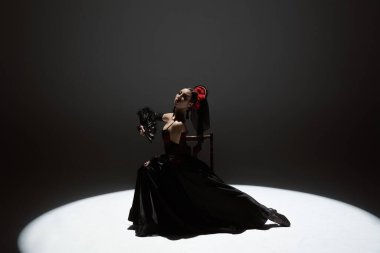 Modern koreografi bir dans. Sahne ışıkları altında siyah arka planda dans eden bir kadın. Kırmızı-siyah elbiseli İspanyol dansçı tutkulu flamenko dansçıları..