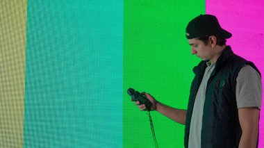 Sahne arkasında teknik servis reklam konsepti. Erkek işçi büyük ekranı kontrol ediyor. Video ekranının ışık seviyesini ölçen lux ölçer cihazlı teknisyen..