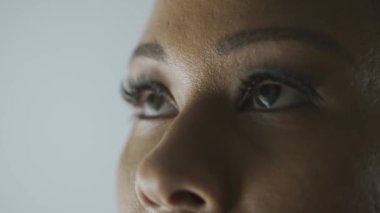Görme bakımı, göz sağlığı hizmetleri konsepti. Kadın modelin makro görüntüsü. Afro-Amerikalı kadın kırpık suratlı, yeşil gözlü, kameradan başka yöne bakan.