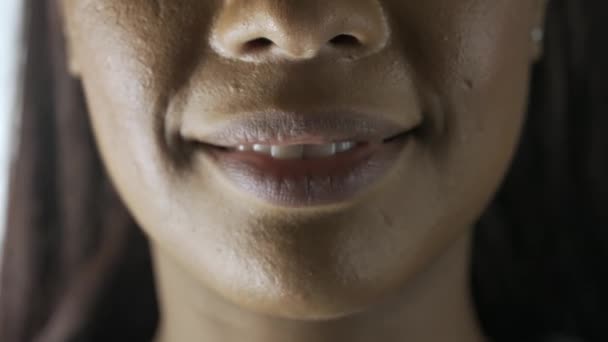 护肤美容服务的概念 女模特脸上的宏观照片 非裔美籍女性的脸部 眼部和嘴唇部位的宏观照片 模特笑着露出牙齿看着相机 — 图库视频影像