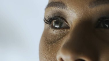 Görme bakımı, göz sağlığı hizmetleri konsepti. Kadın modelin makro görüntüsü. Afro-Amerikalı kadın kırpık suratlı, yeşil gözlü, kameradan başka yöne bakan.