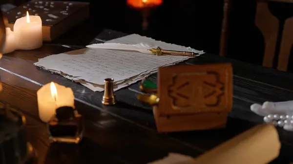 Historical letter creative concept. Desk with aged paper sheets and feather pen. Vintage quill pen laying on old parchment, inkwell box with stamps and lighted candles around.