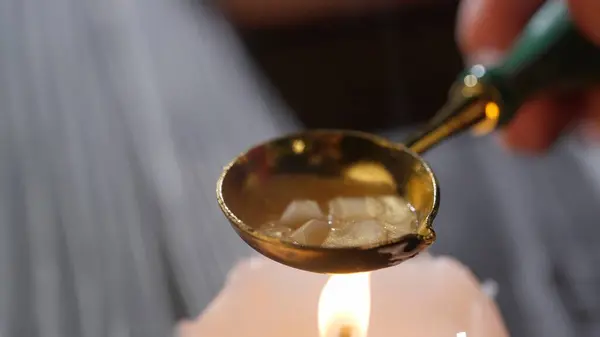 Historical letter creative concept. Female holding golden spoon with sticky liquid. Close up shot of woman warms wax in a golden old spoon on a candle for sealing stamp.