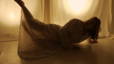 Siluet çağdaş deneysel koreografi konsepti. Stüdyoda kadın dansçı sahne alıyor. Genç kız sıcak arka ışığa karşı dans ediyor..