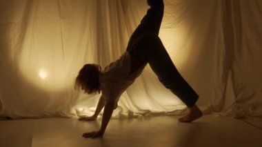 Siluet çağdaş deneysel koreografi konsepti. Stüdyoda kadın dansçı sahne alıyor. Genç kız sıcak arka ışığa karşı dans ediyor..