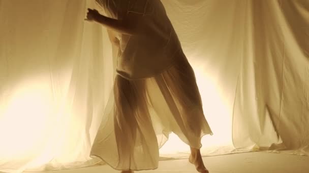 シルエット現代実験振付コンセプト スタジオで踊る女性ダンサー 暖かい背中のライトに対して踊る若い女の子 — ストック動画