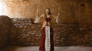 Tarihsel kişi modern yaşam tarzı reklamı. Tarihi iç mekanın arka planında, kadim kıyafetli bir kadın. Rönesans tarzı elbiseli bir kadın kameraya kızgın sinirli bağırarak bakıyor..