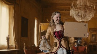 Tarihsel kişi modern yaşam tarzı reklamı. Tarihi iç mekanın arka planında, kadim kıyafetli bir kadın. Rönesans tarzı elbise giymiş kadın elinde karton tabela reklamcılıktan bahsediyor.