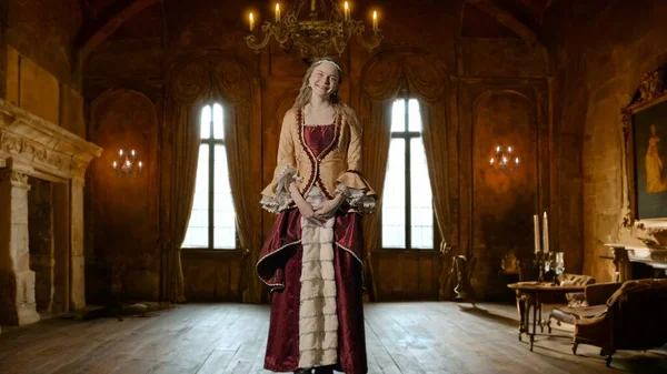 Tarihsel kişi modern yaşam tarzı reklamı. Tarihi iç mekanın arka planında, kadim kıyafetli bir kadın. Rönesans tarzı elbiseli bir kadın kameraya bakıyor, gülümsüyor..