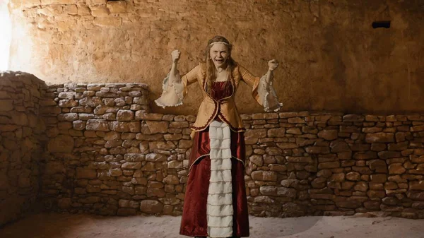 Tarihsel kişi modern yaşam tarzı reklamı. Tarihi iç mekanın arka planında, kadim kıyafetli bir kadın. Rönesans tarzı elbiseli bir kadın kameraya kızgın sinirli bağırarak bakıyor..