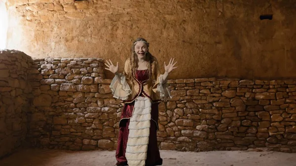 Tarihsel kişi modern yaşam tarzı reklamı. Tarihi iç mekanın arka planında, kadim kıyafetli bir kadın. Rönesans tarzı elbiseli bir kadın kameraya bakıyor, şaşırmış bir yüz..