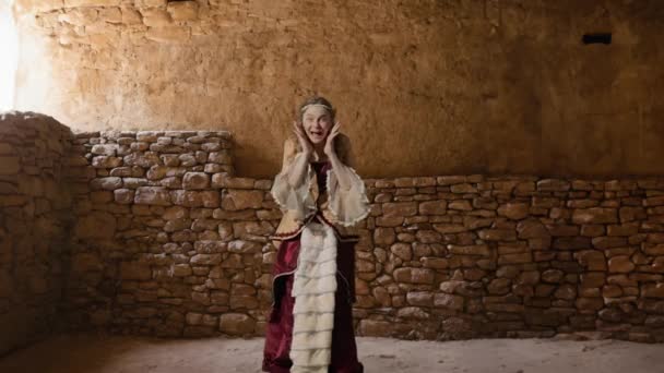 歴史的人物現代ライフスタイル広告 歴史的なインテリアの背景に古代の服を着た女性 カメラを見てルネッサンススタイルのドレスの女性 驚いた顔 — ストック動画