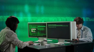 Geleceğin üniversitesi ve yapay zeka konsepti. Büyük dijital ekrana karşı bilişim uzmanları. Erkek ve kadın programcılar dijital kod verileriyle ekranın önündeki bilgisayarlar üzerinde çalışıyorlar.