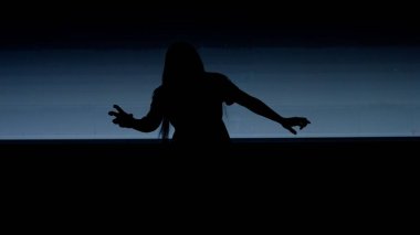 Cadılar Bayramı korku filmi yaratıcı konsepti. Siluet dijital televizyon ekranına karşı. Büyük dijital ekranın önünde beyaz sesli zombi gibi poz veren ürkünç kadın..