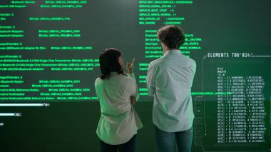 Geleceğin üniversitesi ve yapay zeka konsepti. Büyük dijital ekrana karşı bilişim uzmanları. Kadın ve erkek mühendislerin arka planı. Bilim adamları dijital kod verileriyle ekranın önünde konuşuyor..