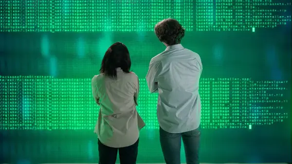 Geleceğin üniversitesi ve yapay zeka konsepti. Büyük dijital ekrana karşı bilişim uzmanları. Kadın ve erkek mühendislerin arka planı. Bilim adamları dijital kod verileriyle ekranın önünde konuşuyor..