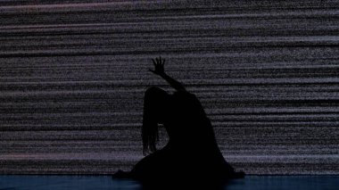 Cadılar Bayramı korku filmi yaratıcı konsepti. Siluet dijital televizyon ekranına karşı. Gerilim sahnesi korkmuş kadın silueti yerde oturmuş gürültüyle büyük dijital ekrana çarpıyor..