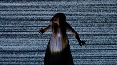 Cadılar Bayramı korku filmi yaratıcı konsepti. Siluet dijital televizyon ekranına karşı. Büyük dijital ekranın önünde beyaz sesli zombi gibi poz veren ürkünç kadın..