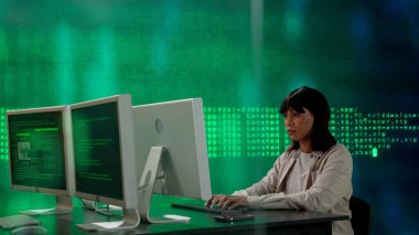 Geleceğin üniversitesi ve yapay zeka konsepti. Büyük dijital ekrana karşı bilişim uzmanı. Afrikalı Amerikalı kadın programcı ekrandaki dijital kod veri sürecinin önünde bilgisayar üzerinde çalışıyor.