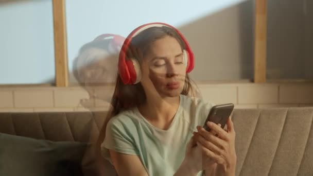 音楽と人間の感情は パーソナリティ広告の概念を分割する 部屋にいる人の肖像 ヘッドフォンの女性は スマートフォンから歌を歌い 感情的に同時に踊ります ダブルエクスポージャー — ストック動画