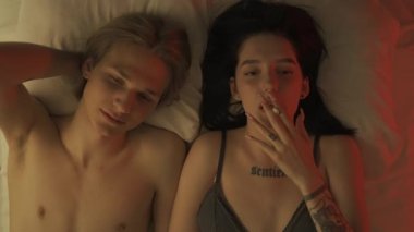 Samimi ilişki kavramını seviyorum. Yatak odasında romantik bir çift manzarası. Erkek ve kadın yarı çıplak, şehvetli aşıklar yatakta birlikte yatıyorlar sigara içiyorlar, tutku bağı kuruyorlar..