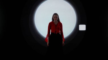 Dijital görsel teknoloji kavramı. Dijital duvara dayanmış bir kadın model. Kırmızı elbiseli kadın, kulüpte arka planda dijital ekranın önünde podyumda yürüyor..