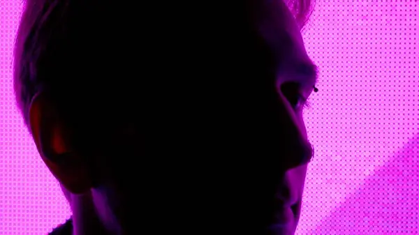 デジタルビジュアルテクノロジーコンセプト 大きなデジタル壁に対する男性 ダーククラブのネオンシンボルでデジタルスクリーンウォールの前で撃たれた男の顔のシルエット — ストック写真