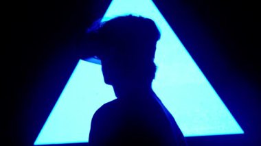 Dijital görsel teknoloji kavramı. Sanal gerçeklik gözlüklü bir adam silueti dijital ekran duvarının önünde duruyor ve etrafa bakıp video oyunu oynuyor..