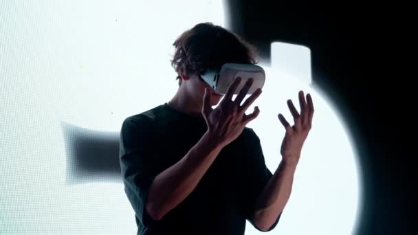 デジタルビジュアルテクノロジーコンセプト デジタルスクリーンの壁の前に立っている仮想現実のガラスの男のシルエットは手を握るまわりを見回す抽象的なシンボルを妨げます — ストック動画