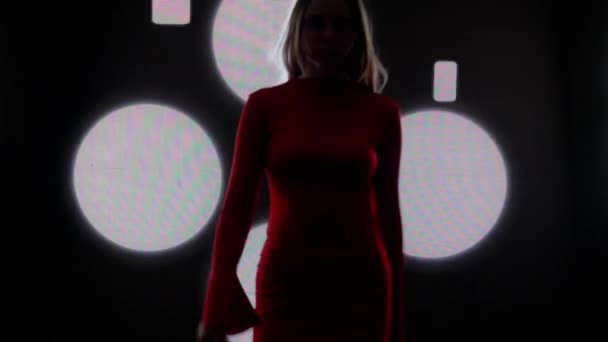 デジタルビジュアルテクノロジーコンセプト デジタル壁に対する女性モデル クラブのデジタルスクリーンウォールの背景の前に逃げ道のキャットウォークファッションショーを歩く赤いドレスの女性 — ストック動画