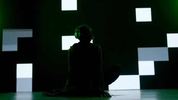 サイバーパンクビジュアルテクノロジークリエイティブコンセプト スタジオの大きなデジタル壁に反対する人 デジタルスクリーンサイバーグラフィックビジュアル背景 バックショットの前に座っているバーチャルリアリティメガネの男 — ストック写真