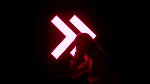 デジタルビジュアルテクノロジーコンセプト ダーククラブのデジタル壁に対抗するノートパソコンを持つ若い女性 ラップトップに座っている女性のシルエット ゲームミキシング音楽 ストロボネオンシンボルデジタルスクリーン — ストック動画