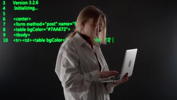 サイバーパンクビジュアルテクノロジークリエイティブコンセプト スタジオの大きなデジタル壁に反対する人 ラップトップのハッキングサーバーデータベース サイバーコードデータビジュアル背景を持つデジタルスクリーンを持つ女性ハッカー — ストック動画