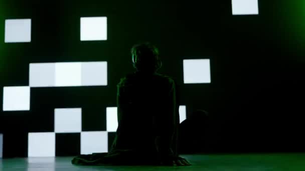 サイバーパンクビジュアルテクノロジークリエイティブコンセプト スタジオの大きなデジタル壁に反対する人 デジタルスクリーンサイバーグラフィックビジュアル背景 バックショットの前に座っているバーチャルリアリティメガネの男 — ストック動画