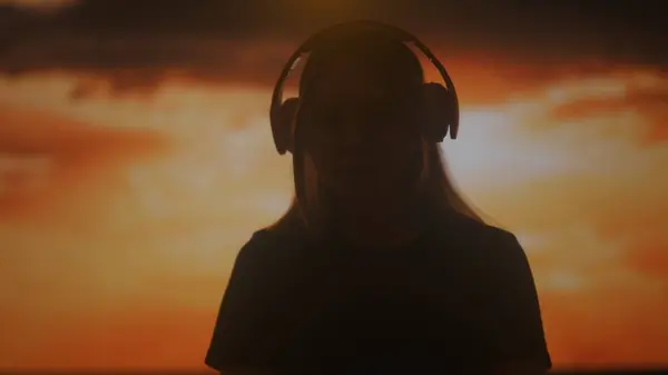 Büyük Kulaklıklarla Müziğin Keyfini Çıkaran Bir Kadının Silueti Batan Güneşin — Stok fotoğraf
