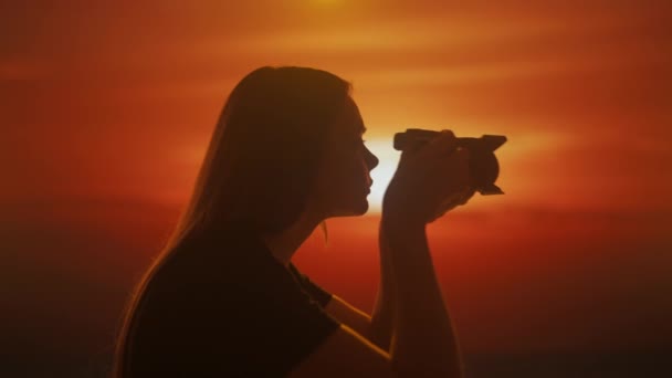 Silhueta Uma Jovem Fêmea Tirando Uma Foto Com Uma Câmera — Vídeo de Stock