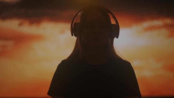 Силует Жінки Яка Насолоджується Музикою Великих Навушниках Захоплюється Теплим Сяйвом — стокове відео