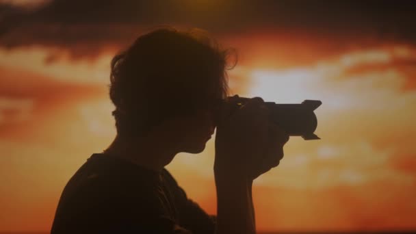 Gün Batımının Parlak Gölgesinde Kamerayla Fotoğraf Çeken Genç Bir Erkeğin — Stok video