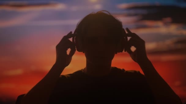 Sylwetka Mężczyzny Cieszącego Się Muzyką Dużych Słuchawkach Uchwycona Ciepłym Świetle — Wideo stockowe